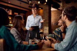 Restaurant server taking an order at a busy bar, illustrating fast, discreet team coordination in hospitality during peak service.