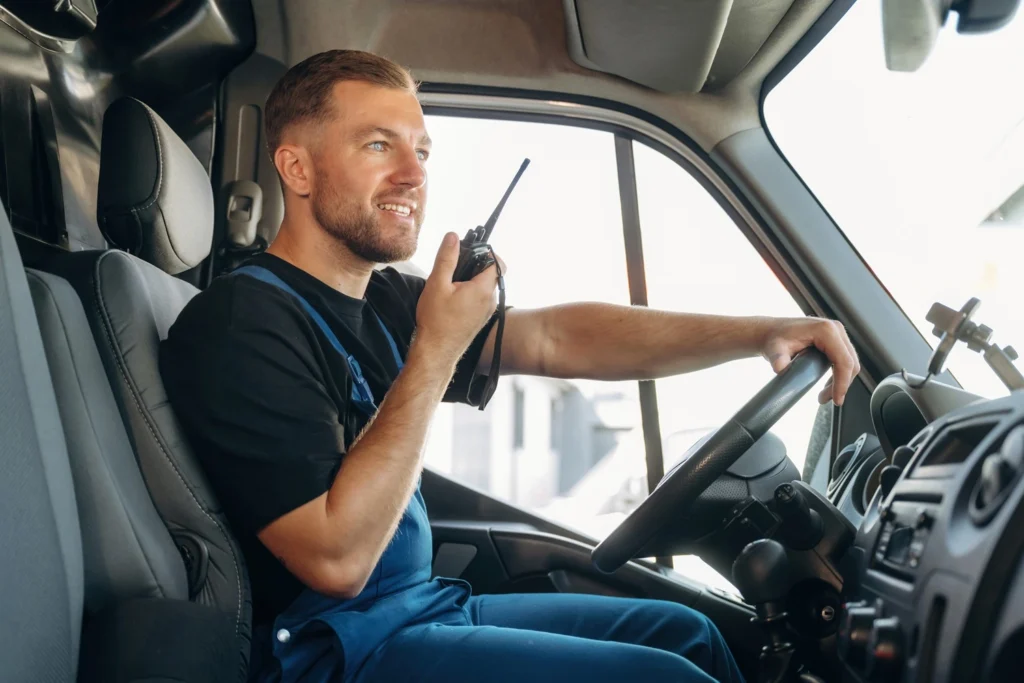 Fleet driver using a two way radio from the cab of a van, coordinating roadside jobs with dispatch.